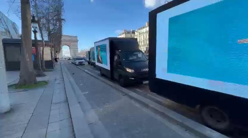 Camions publicitaires LED alignés sur les Champs-Élysées près de l'Arc de Triomphe