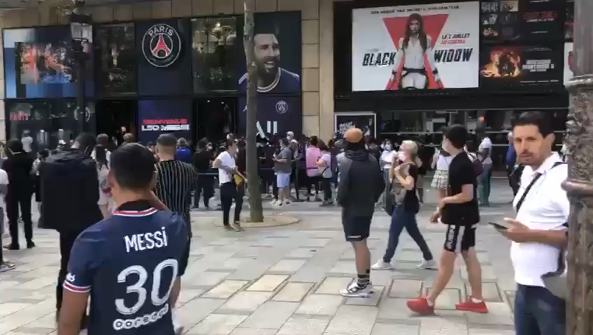 Foule rassemblée lors d'une activation de rue devant une boutique parisienne